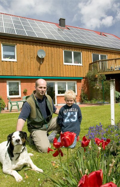 Mann mit Kind vor Photovoltaik Referenzanlage